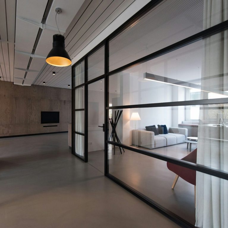 Modernes Raumdesign mit Glaswänden, minimalistischen Möbeln und einer gemütlichen Atmosphäre.