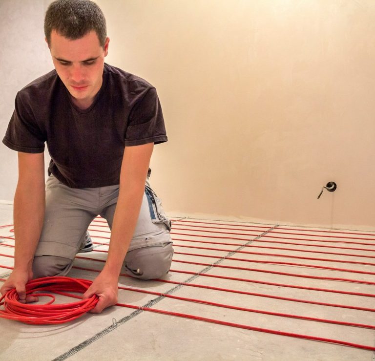 Handwerker installiert Fußbodenheizungsleitungen auf einem Fußboden.